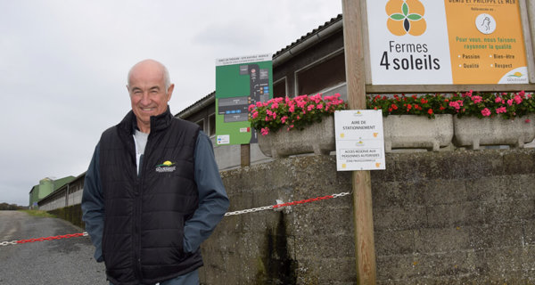 Denis Le Mer devant entrée du site avicole avec panneaux et chaîne