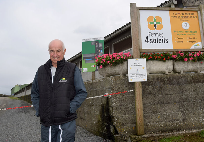 Denis Le Mer devant entrée du site avicole avec panneaux et chaîne